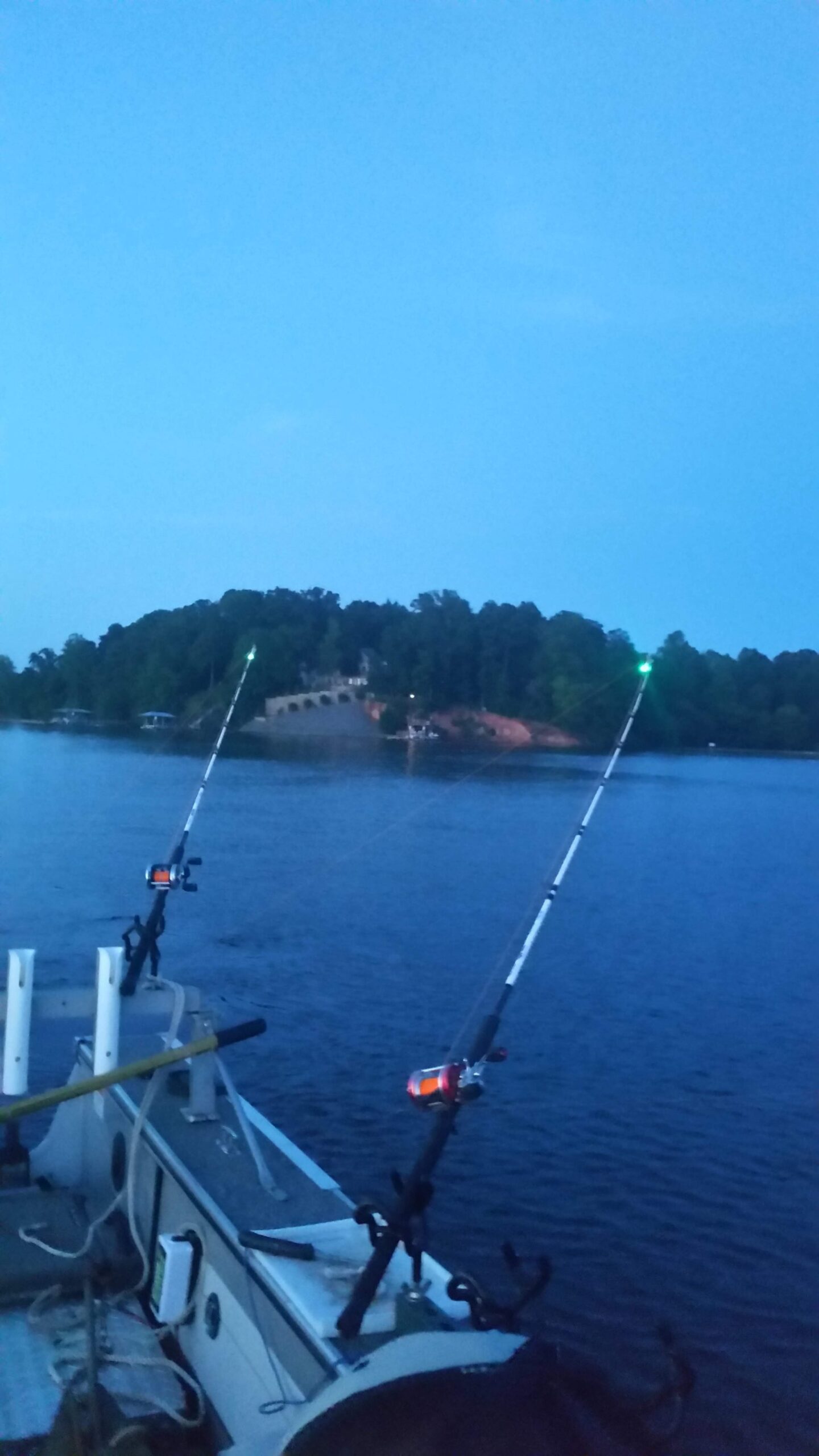 Two fishing poles are in the water near a small island.